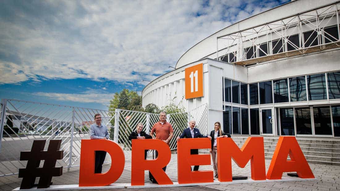 Grupa osób związanych z organizacją targów DREMA 2025 przed wejściem do hali w Poznaniu, obok instalacji z napisem #DREMA. Symboliczne zdjęcie otwarcia lub zakończenia wydarzenia.