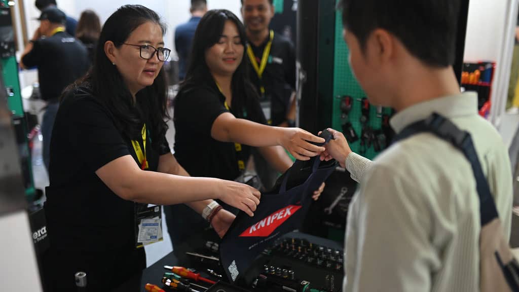 Personel stoiska Knipex wręcza torbę z narzędziami kupcowi na targach International Hardware Fair Indonesia w Dżakarcie.