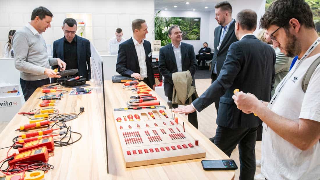 Grupa handlowców i dystrybutorów przy stoisku z prezentacją narzędzi ręcznych, mierników elektrycznych i kluczy na targach International Hardware Fair.