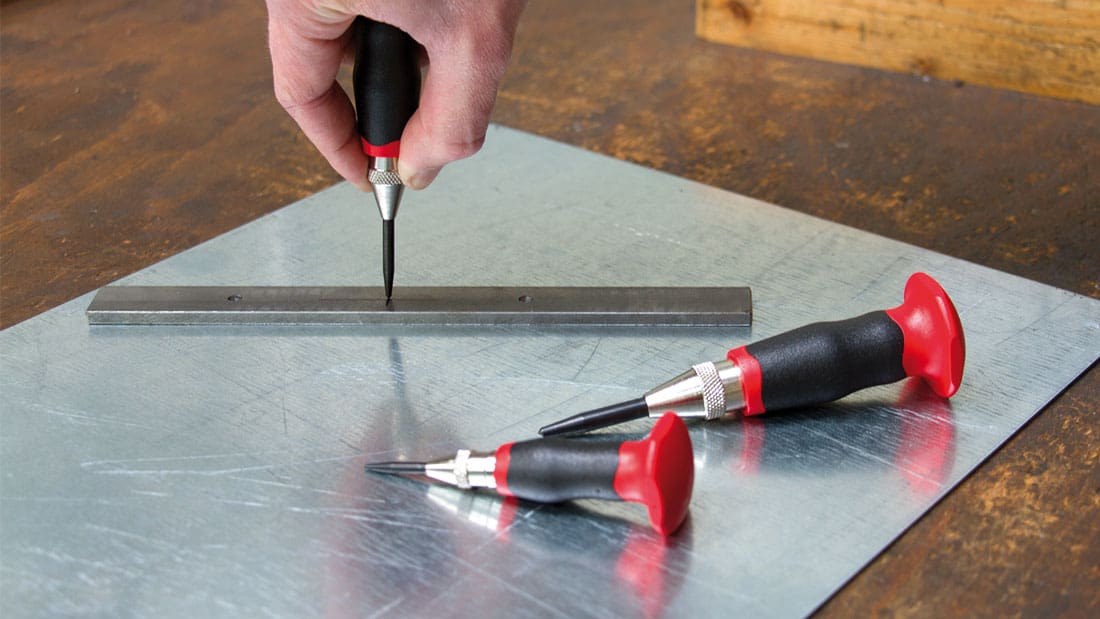 Użycie punktaka automatycznego Rennsteig z dwukomponentową rękojeścią do trasowania punktu na blasze metalowej.