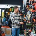 Instalator wybierający sprzęt z bogatej oferty hurtowni; zbliżenie na klienta przy regale z narzędziami.