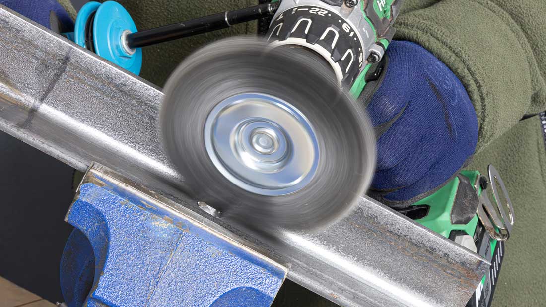 Szczotka druciana Klingspor BRS 300 W na wiertarce czyszcząca płaską powierzchnię stalowego profilu w imadle.