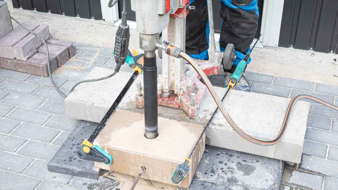 Wiercenie otworu w bloczku betonowym koroną diamentową Kinczyk KWK-B zamocowaną w wiertnicy diamentowej, praca na mokro