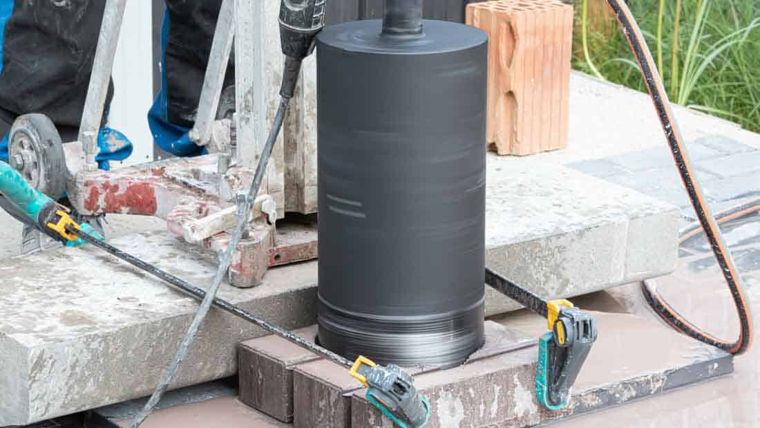 Korona diamentowa Kinczyk KWK-B podczas wiercenia w betonie konstrukcyjnym, stabilizacja elementu za pomocą zacisków