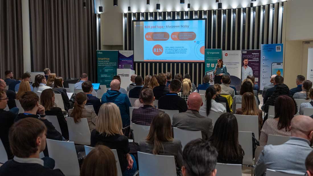 Pełna sala słuchaczy podczas prelekcji na konferencji E-commerce B2B 2025. Na ekranie widoczny slajd z kluczowymi statystykami rynku.