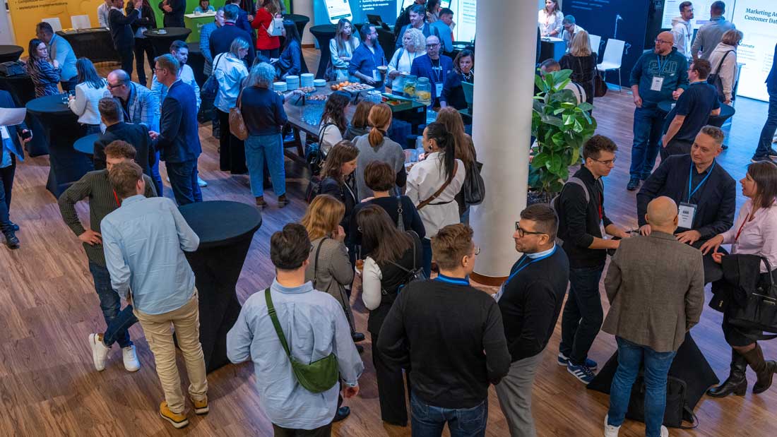 Uczestnicy konferencji rozmawiający w grupach podczas przerwy networkingowej w strefie cateringowej