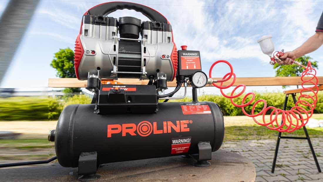 Kompresor bezolejowy PROLINE P200003 z 9-litrowym zbiornikiem podczas przedmuchiwania elementów drewnianych na zewnątrz