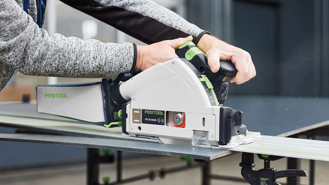 Pilarka zagłębiarka Festool TSC 55 KS pracująca na szynie prowadzącej przy cięciu płyty meblowej w warsztacie
