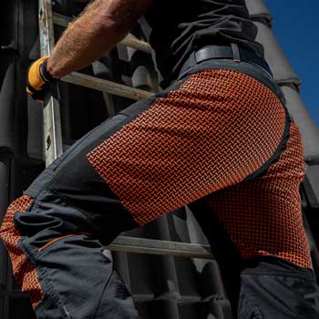 Zbliżenie na spodnie robocze LAHTI PRO noszone przez dekarza podczas pracy na wysokości na dachu
