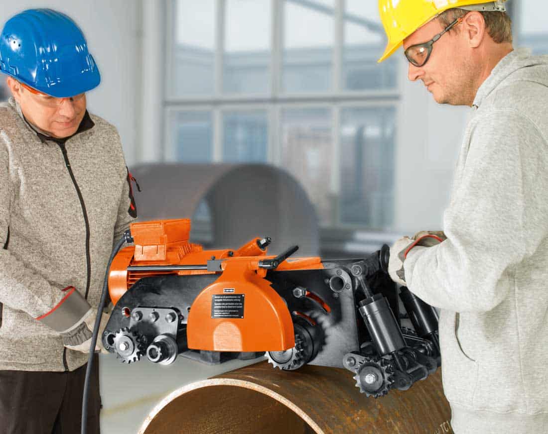 Dwóch operatorów montuje frezarkę do rur FEIN z łańcuchowym systemem mocowania na stalowej rurze