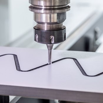 Zbliżenie na grawerowanie kształtowe w płycie HPL na maszynie CNC – jednolita głębokość nacięcia i gładkie krawędzie