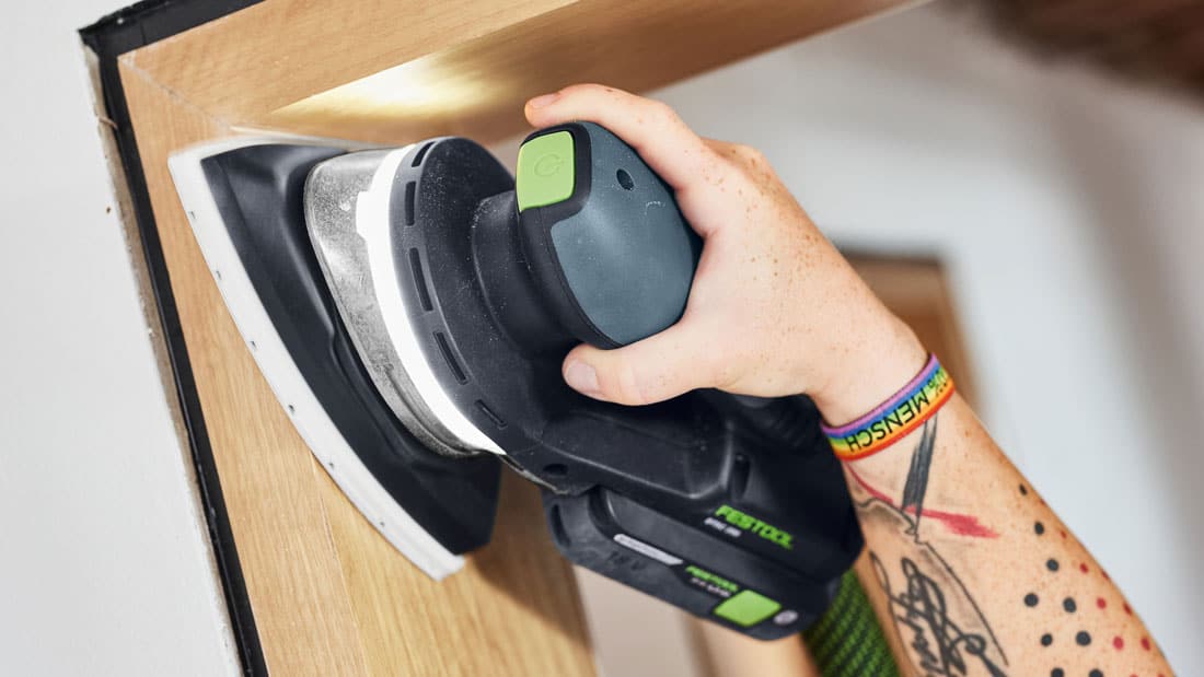 Szlifowanie narożnika drewnianej ramy za pomocą akumulatorowej szlifierki delta Festool DTSC 200 z podświetleniem LED i stopą trójkątną.