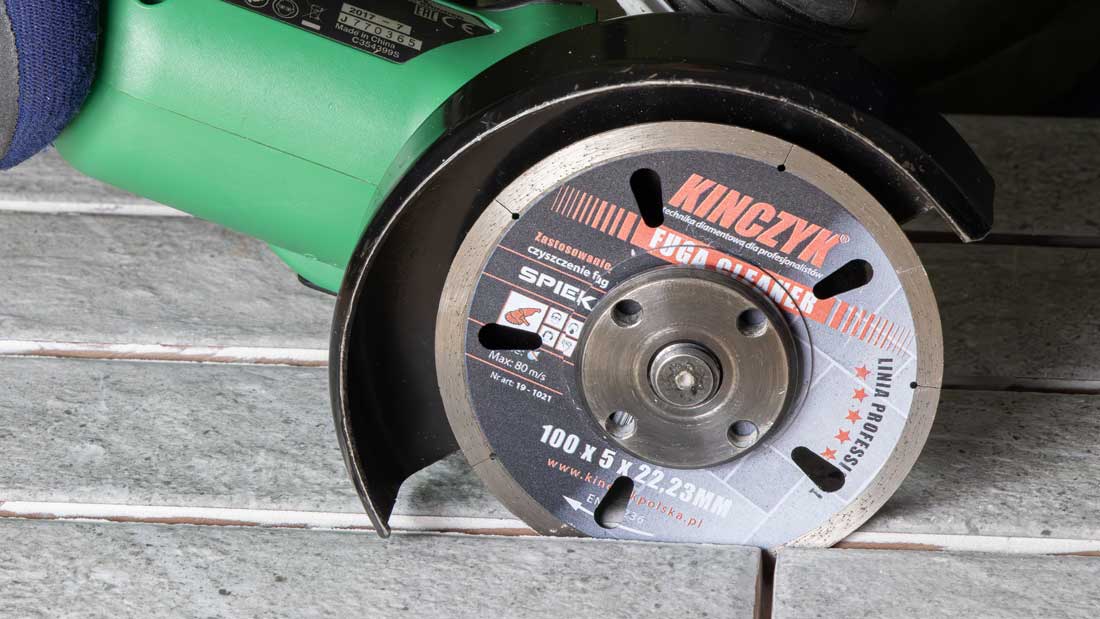 Szlifierka kątowa z tarczą diamentową KINCZYK FUGA CLEANER podczas precyzyjnego wycinania fugi w okładzinie z płytek.