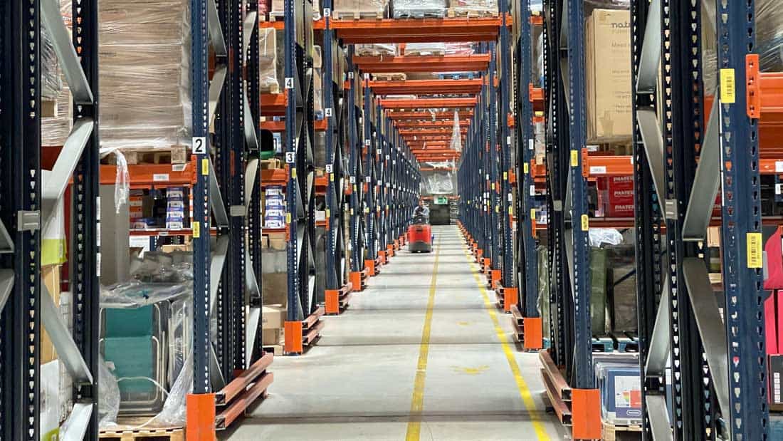 Magazyn wysokiego składowania w centrum logistycznym dystrybutora produktów DIY z regałami paletowymi i systemem kompletacji zamówień.