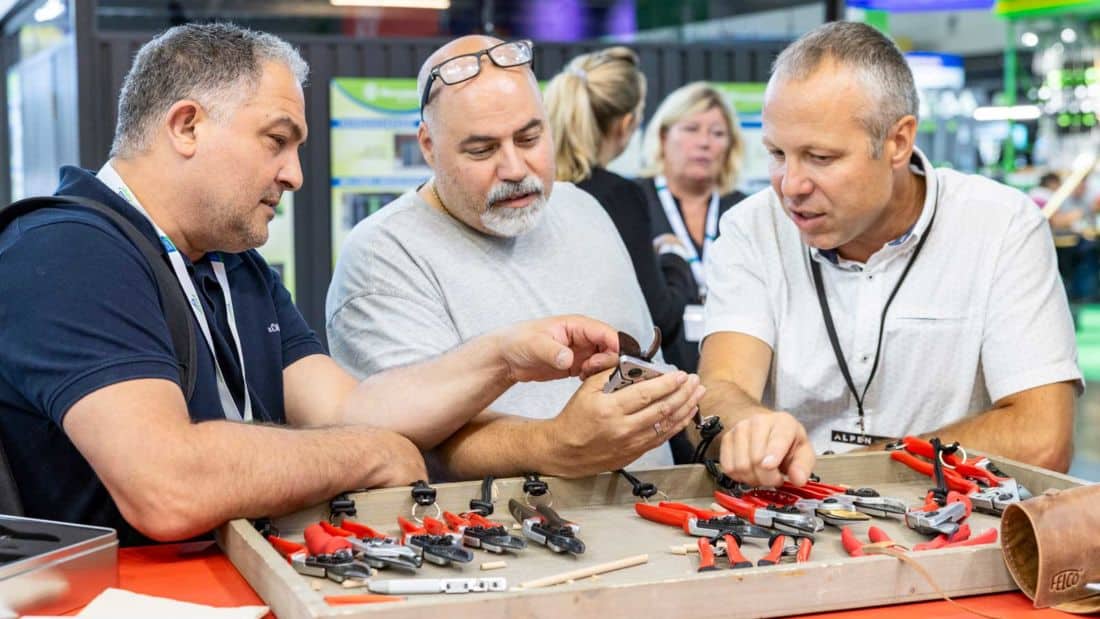 Uczestnicy targów spoga+gafa oglądają i testują sekatory ogrodowe na stoisku wystawcy, prezentacja narzędzi do przycinania roślin
