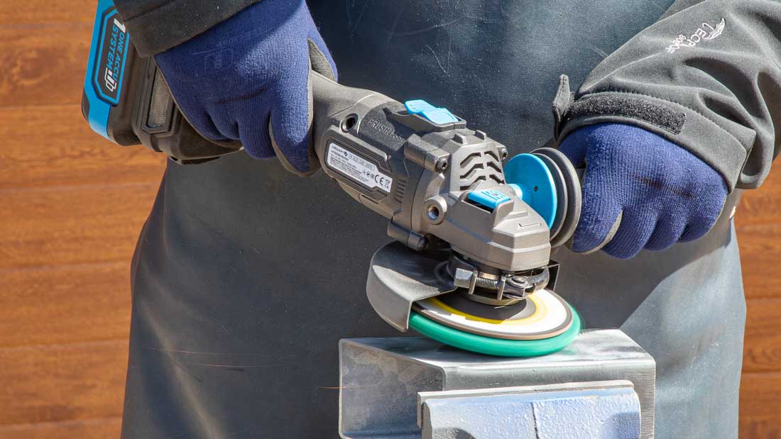 Högert Technik HT2E282-B24AG – precyzyjne szlifowanie elementu stalowego w imadle tarczą włókninową, kontrolowana praca urządzenia