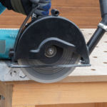 Szlifierka kątowa z osłoną i tarczą diamentową Kinczyk Beton C1 podczas cięcia materiału budowlanego