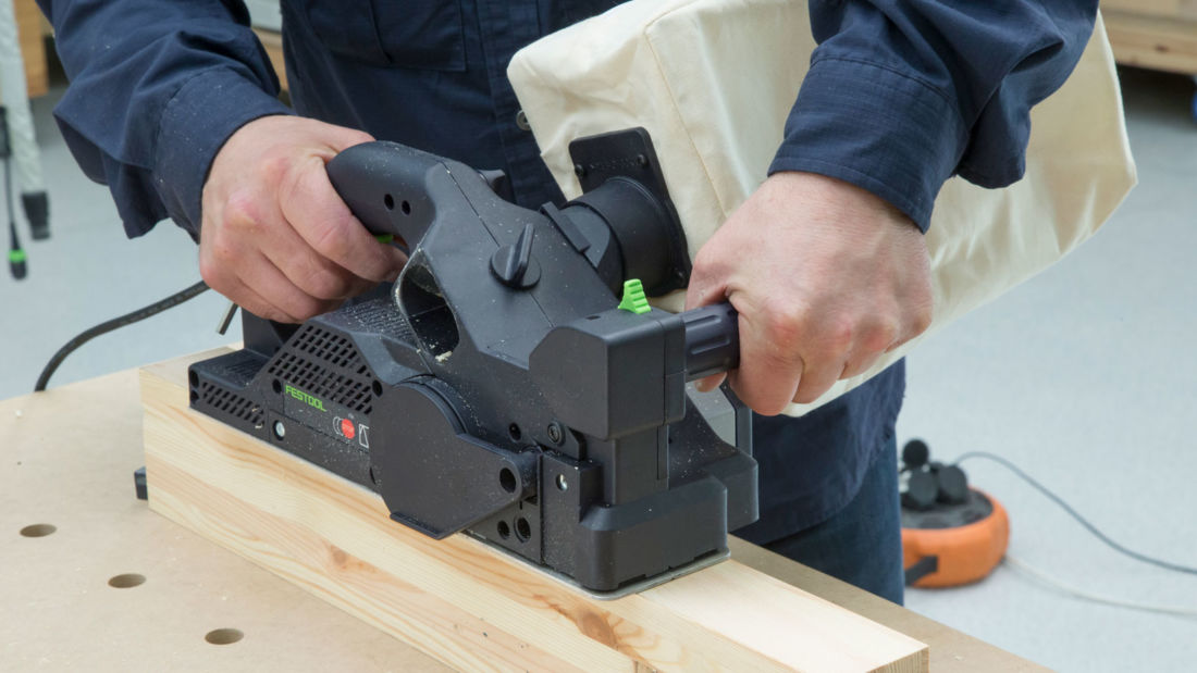 Strugarka elektryczna Festool HL 850 EB podczas obróbki drewnianej belki w warsztacie stolarskim.