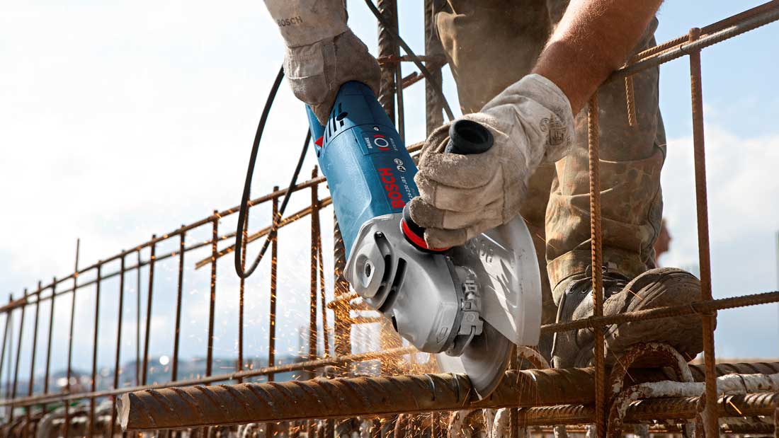 Pracownik budowlany przecina zbrojenie szlifierką kątową Bosch Professional podczas robót konstrukcyjnych.